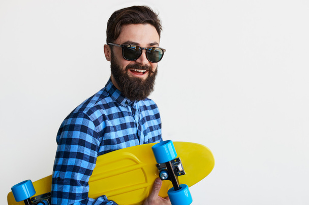 Handsome young man holding yellow skateboard - Zdjęcie, obraz