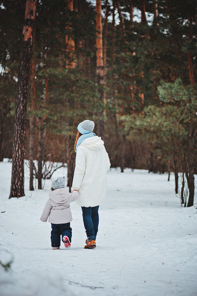 winter portrait of cute baby girl in oversize grey knitted scarf walking in snowy forest - Zdjęcie, obraz