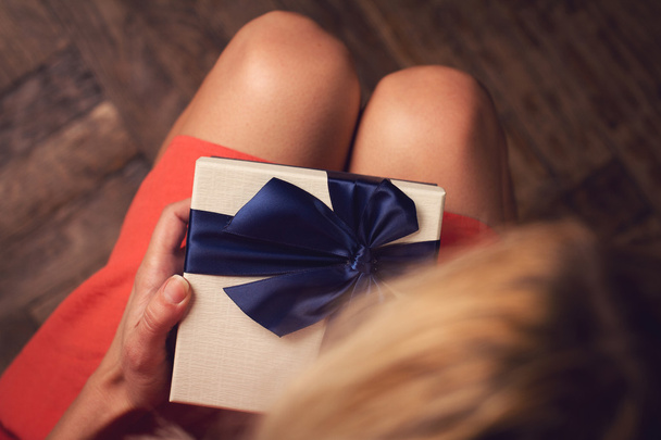  Frau öffnet einen Geschenkkarton mit blauem Band - Foto, Bild