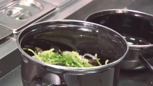 Cocine añadir la albahaca del recipiente de plástico en la sartén con mejillones, vegetación en la mesa. Restaurante cocina
 - Metraje, vídeo