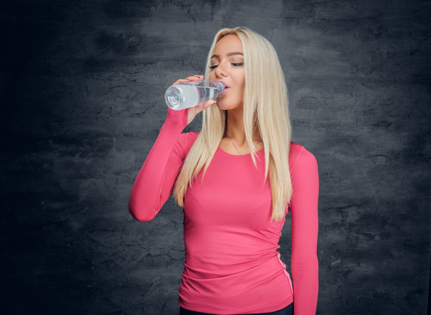 Ξανθιά γυναίκα πίνοντας ένα μπουκάλι νερό. - Φωτογραφία, εικόνα