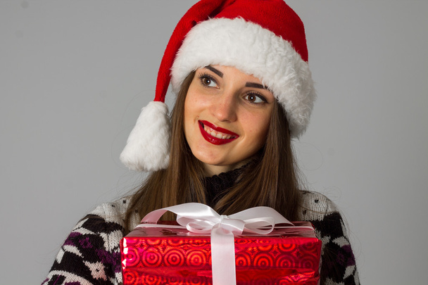 woman in warm sweater and santa hat with red gift - Fotografie, Obrázek