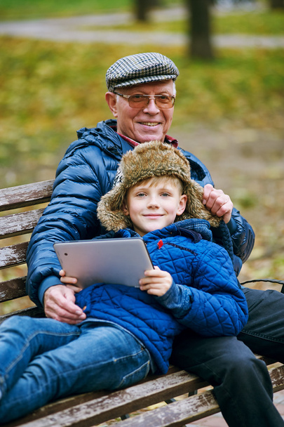 Онук з Дідом в Осінній Парк та читання за допомогою планшета - Фото, зображення