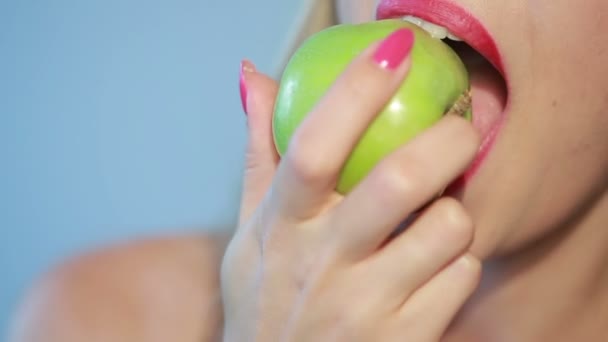 beautiful girl eats a green apple on a blue. close-up - Metraje, vídeo