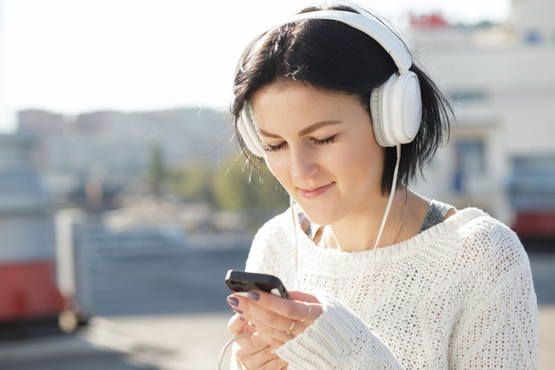 Woman in white earphones listen music outdoor - Photo, Image