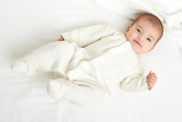baby portait lie on white towel in bed, yellow toned - Foto, Imagem