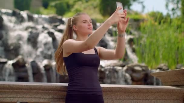 Selfie-tyttö. Valkoihoinen tyttö ottaa selfietä vesiputouksen lähellä. Selfie nainen
 - Materiaali, video