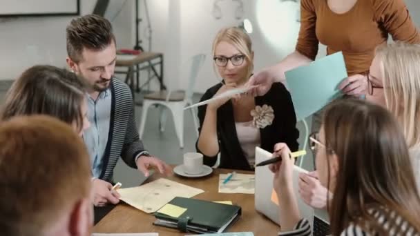 Creative business team at the table in a modern startup office. Female leader explains the details of the project. - Video