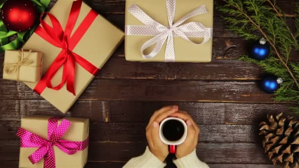 Felülnézet kezek karácsonyi ajándékokat a fenti táblázatban kávé, tea - Felvétel, videó