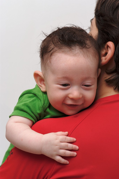 Vue arrière de mignon bébé garçon souriant regardant par-dessus l'épaule de la mère
 - Photo, image