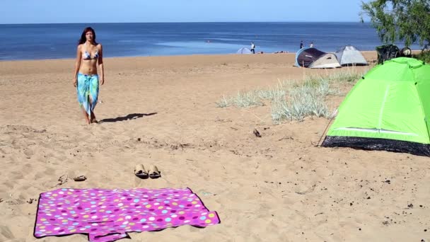 Το κορίτσι sunbathes σε ένα χαλί στην παραλία - Πλάνα, βίντεο
