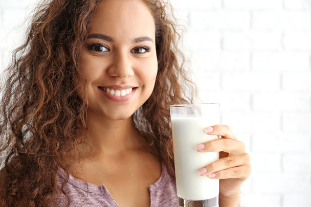 Привлекательная молодая африканская женщина со стаканом молока
 - Фото, изображение