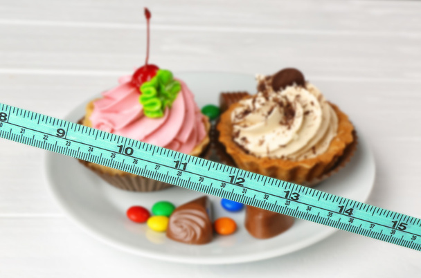 Measuring tape and plate with delicious cakes - Photo, image