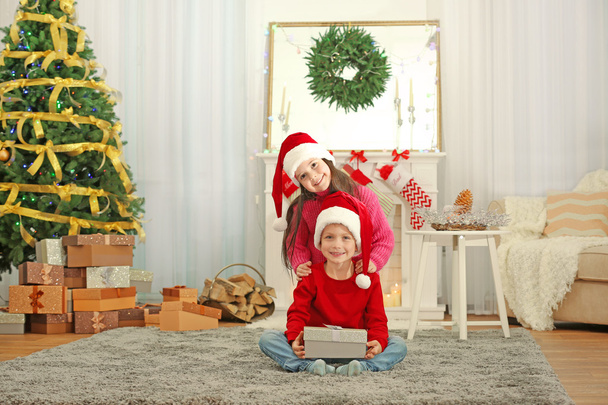 Cute little kids in Santa hats with Christmas present at home - Fotoğraf, Görsel