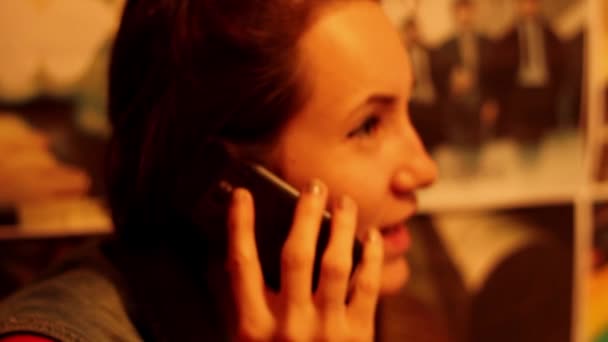 Meisje is praten over de telefoon op een gekleurde achtergrond emotioneel - Video