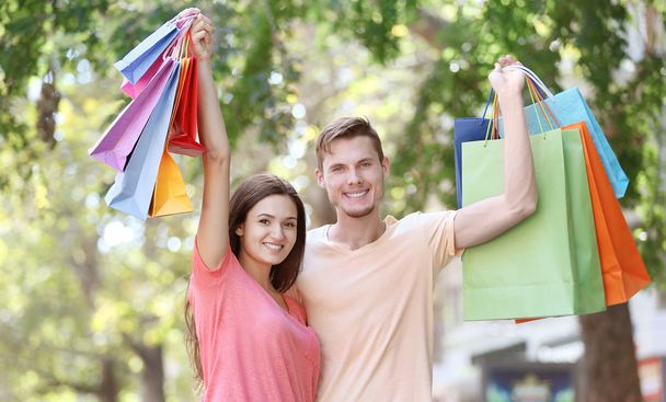 Happy couple with colorful shopping bags in park - Foto, Imagem