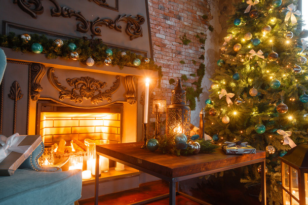 Christmas evening by candlelight. classic apartments with a white fireplace, decorated tree, sofa, large windows and chandelier. - Foto, afbeelding