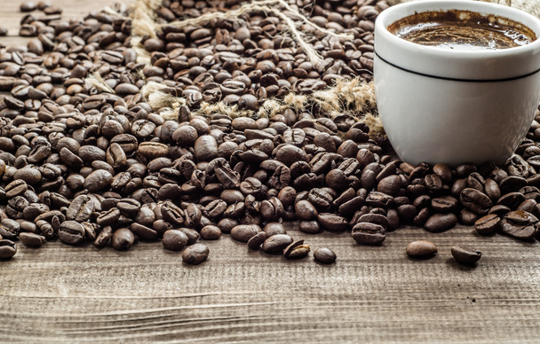 Cup of coffee and coffee beans on wooden table, overhead - Foto, Imagen