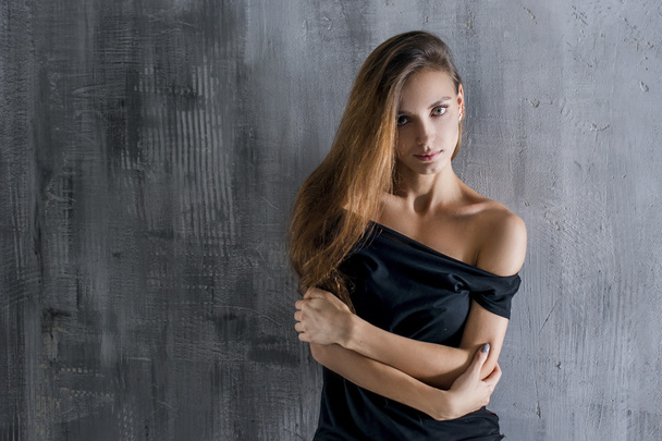 Beautiful young woman on dark grey wall background - Foto, Bild