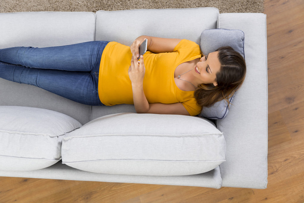 жінка в жовтій футболці лежить на дивані
 - Фото, зображення