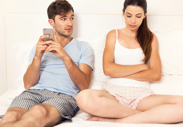 man on bed with cellphone looking at woman   - Foto, immagini