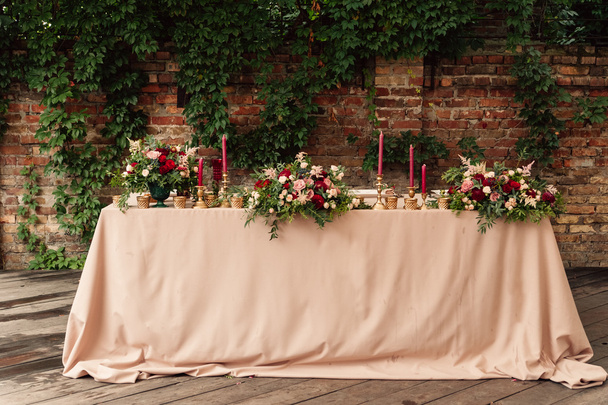 Décor de table de zone de mariage avec des fleurs rouges et des bougies en or - Photo, image