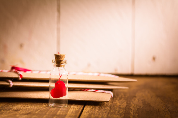 Послание любви в бутылке с ширмой на деревянном столе, винтажный тон - Фото, изображение