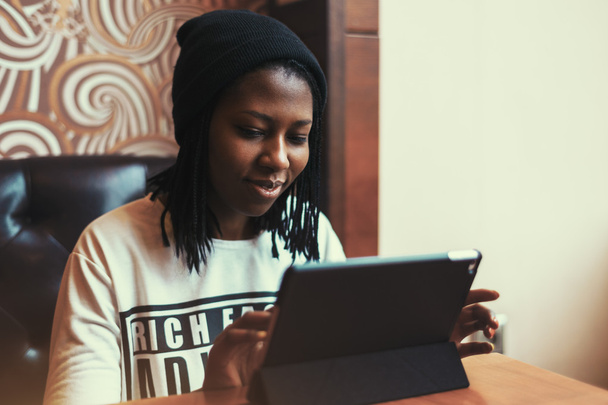 Красива чорна дівчина посміхається і працює на планшеті в кафе
 - Фото, зображення