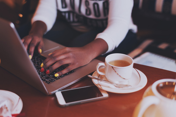 Чорні руки з різнокольоровими цвяхами на клавіатурі ноутбука в кафе
 - Фото, зображення