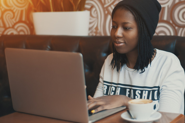 Jovem menina negra no café trabalhando no laptop
 - Foto, Imagem