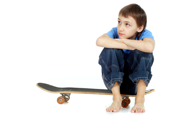 Boy sitting on skateboard - 写真・画像