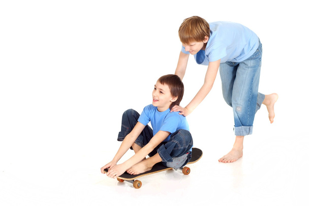 Deux garçons sur une planche à roulettes
 - Photo, image