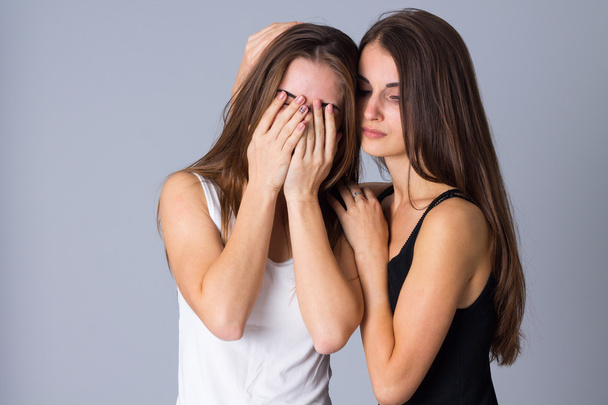 One woman crying and another embracing her - 写真・画像