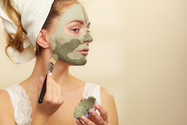 Woman applying with brush clay mud mask to her face  - Foto, Bild