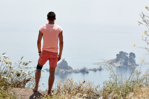 Homem olha para o mar e rochas
 - Foto, Imagem