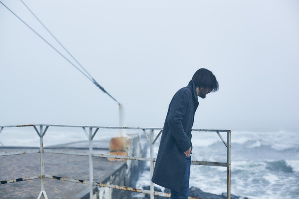 Mann im grauen Mantel geht am Meer spazieren - Foto, Bild