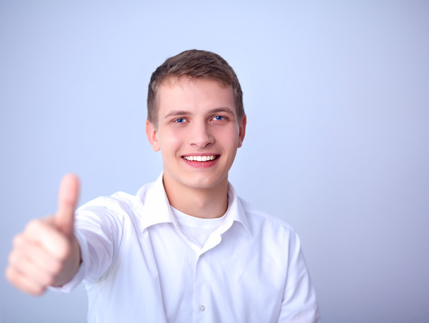 Portrait of young man smiling sitting on gray background - Φωτογραφία, εικόνα
