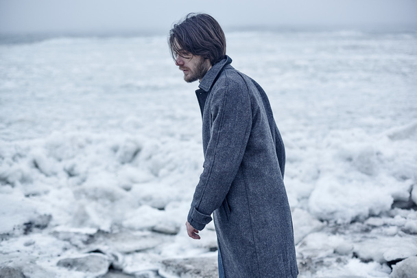 Man in a gray coat walking near sea - Photo, Image