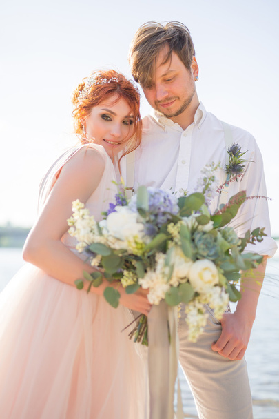 la pareja feliz novio y novia con ramo de bodas están en la playa
 - Foto, Imagen