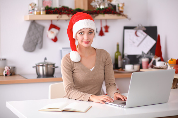 Smiling young woman in the kitchen, isolated on christmas background - Foto, Imagem