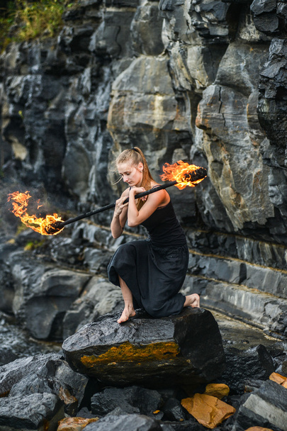 Girl in a black suit with flaming torches . - Photo, Image