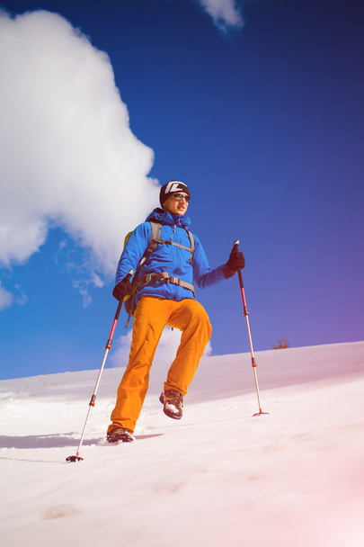 Alpinista idzie na zaśnieżonym stoku. - Zdjęcie, obraz
