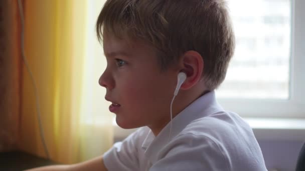 het kind luistert naar muziek op smartphone in de hoofdtelefoon en hop hoofd in huis - Video