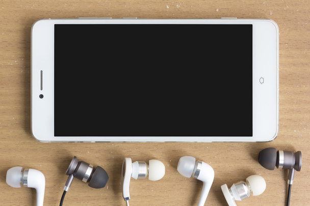 Смартфон і навушники на столі
 - Фото, зображення