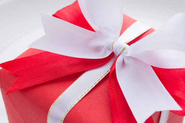 rode geschenkdoos met rode en witte strik op witte achtergrond - Foto, afbeelding