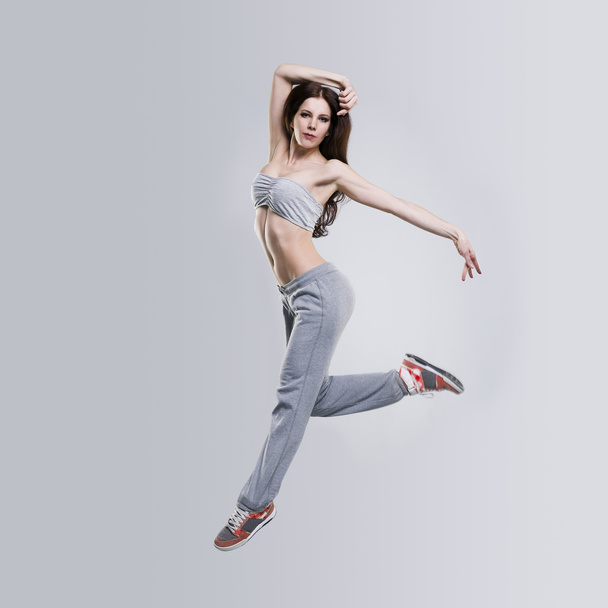 Beautiful young woman dancer jumping in studio - Фото, зображення