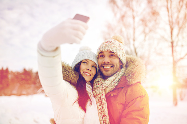 happy couple taking selfie by smartphone in winter - Foto, afbeelding