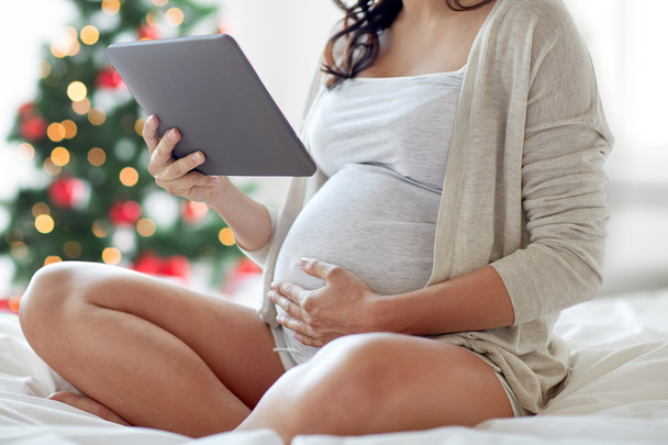 close up of pregnant woman with tablet pc at home - Foto, imagen