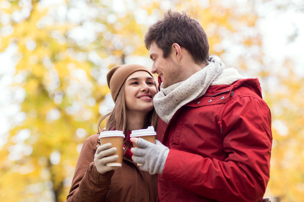 happy couple with coffee walking in autumn park - 写真・画像