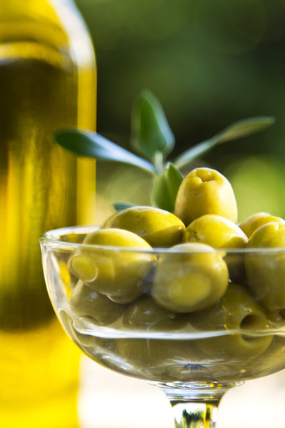 glass cup filled with olives and olive oil bottles - Foto, Imagem